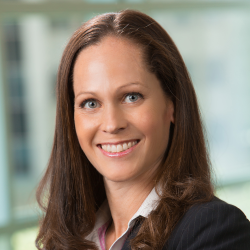 Nicole Mossman, woman smiling with long, brown hair wearing blouse with dark suit jacket